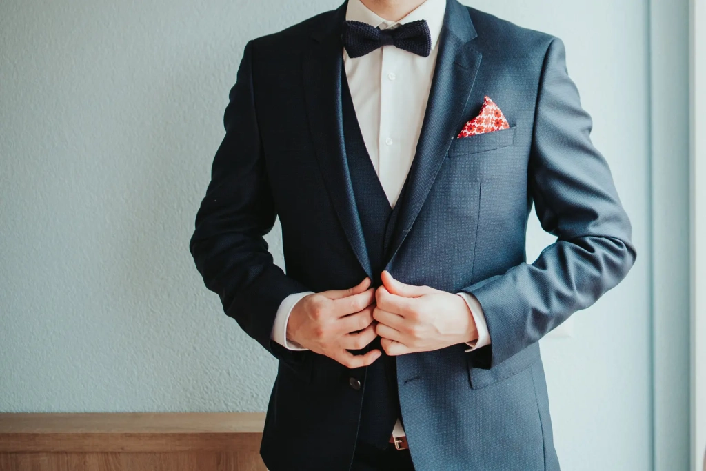 man dressed in a fine suit with bowtie buttoning
